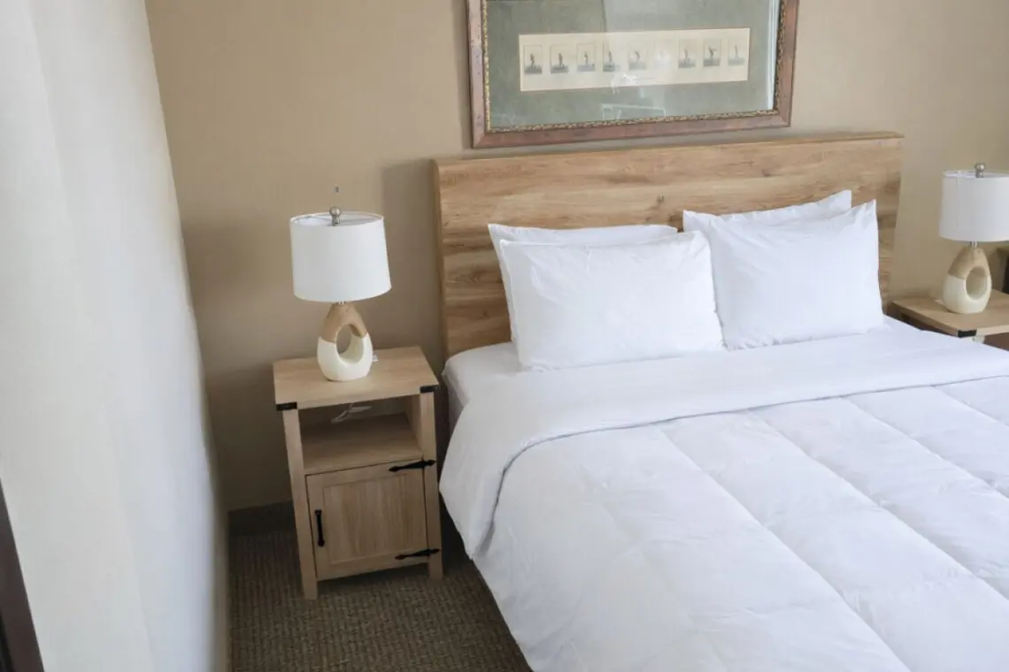 Single queen hotel room at Nisswa Hotel & Suites in Nisswa MN with comfortable bed and bedside lighting