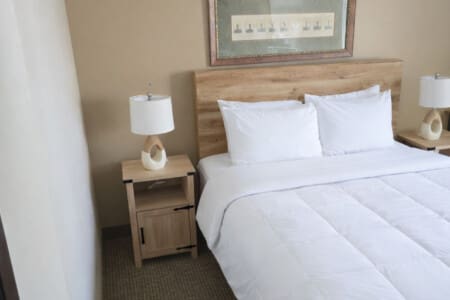 Single queen hotel room at Nisswa Hotel & Suites in Nisswa MN with comfortable bed and bedside lighting